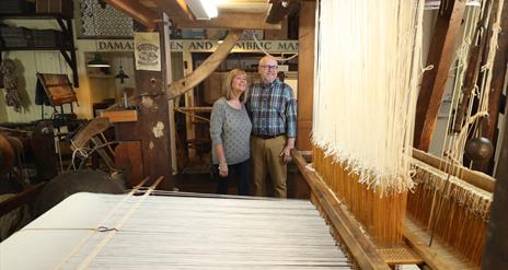 Couple viewing a linen weaving loom.