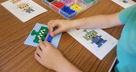 Close up photo of a child's hands constructing a toy model from Lego bricks