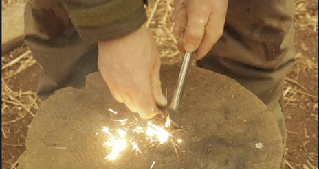 Bushcraft. Hands lighting fire on stone