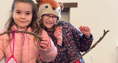 Two girls proudly holding their craft they made with twigs at the Forest Activities event.