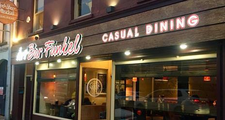 picture showing the front of resturantlit up at night time.