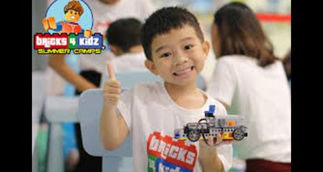 A child enjoying a lego workshop with his thumb up