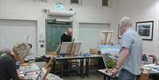 A photograph of Martin McParland painting on a canvas in Down Arts Centre whilst leading an acrylic painting course.