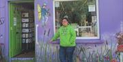 Pictured is Belinda, owner of the souvenir shop standing infron of the building. On the front is a graphic of a black sheep and also a green sheep wit