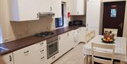 Kitchen with table & chairs, hob/oven, microwave, fridge, washing machine and the back door.