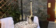 outdoor seating area with two glasses and a bottle of champagne