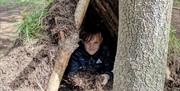 Boy looking out of camp under tree