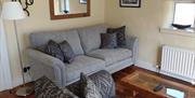 A view of a grey living room sofa with a lamp, coffee table and a small window.