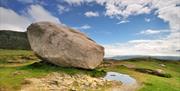 A picture of the side view of cloughmore stone with a small puddle infront.