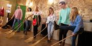 Group dancing with brooms as part of the Dancing at the Crossroads experience