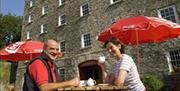 A couple enjoying a cup of tea at a picnic table outside of the mill.