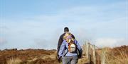 Couple walking alongside fenced area.
