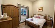 Large double bedroom with bedside drawers, a wardrobe and a window.