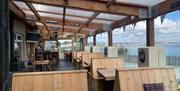 Outside dining area of The Harbour House Inn with wooden benches overlooking the stunning sea