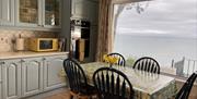 Kitchen cupboards, table and sea view through large window