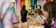 Lady showing demonstration to kids at painting class