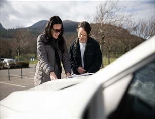 Couple outside a hire vehicle looking at a map.