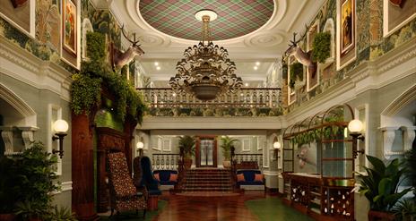 Grand lobby of Slieve Donard with dark wooden floors, lots of greenery and a large chandelier.
