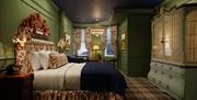 Guest room at Slieve Donard with green walls, a tartan carpet, floral bed and headboard.