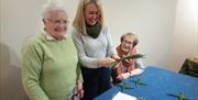 3 women enjoying making St Brigid Crosses at the Legacy of Saint Brigid Experience in the St Patrick Centre.