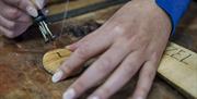 An up-close photo showing how the imprinting on to wooden pendants is done