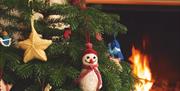 Picture displaying a knitted snowman and a star hanging on a Christmas tree.