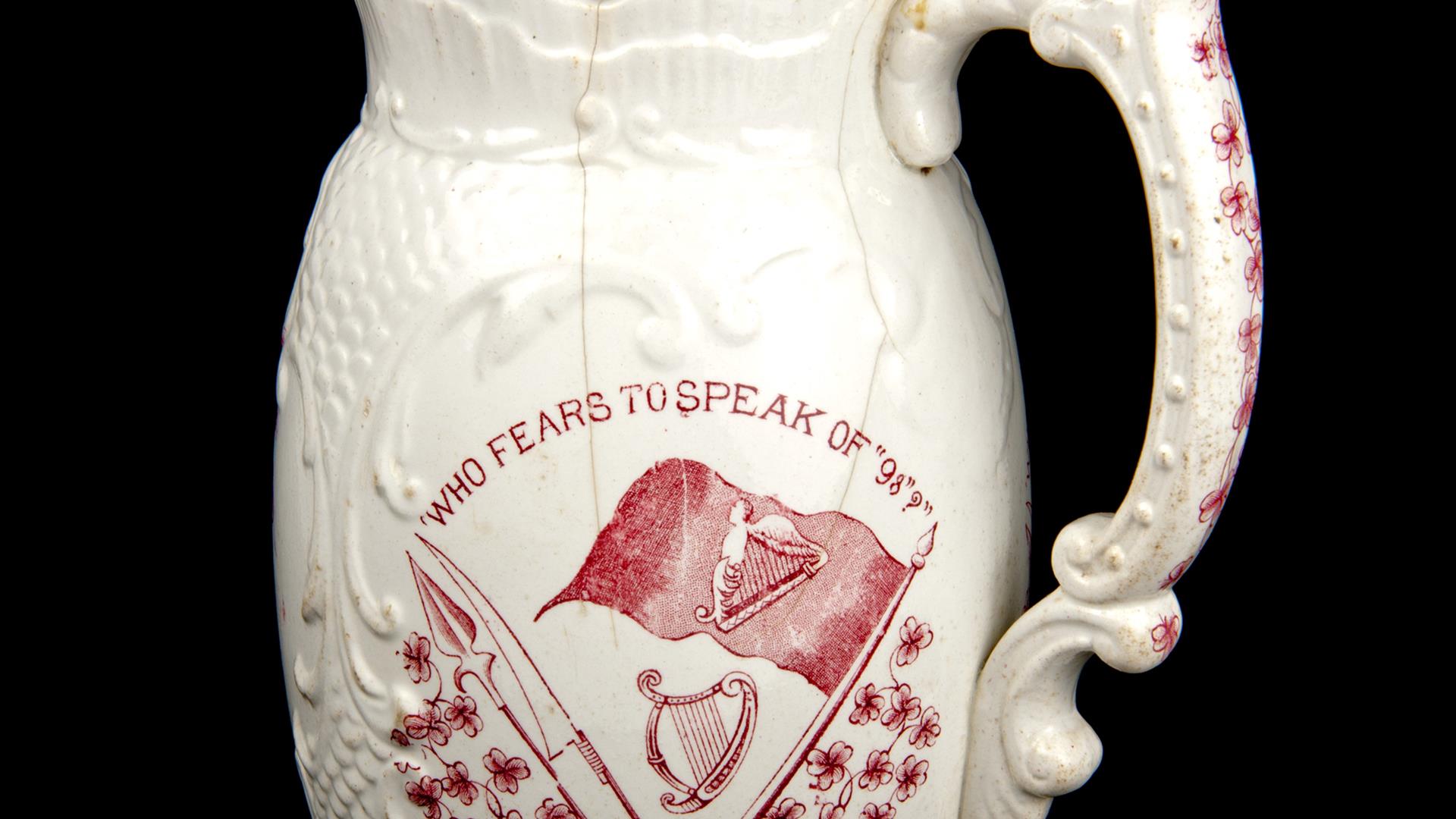 A jug printed with the phrase 'who fears to speak of '98?'  in red, which was made to commemorate the centenary of the 1798 rebellion.