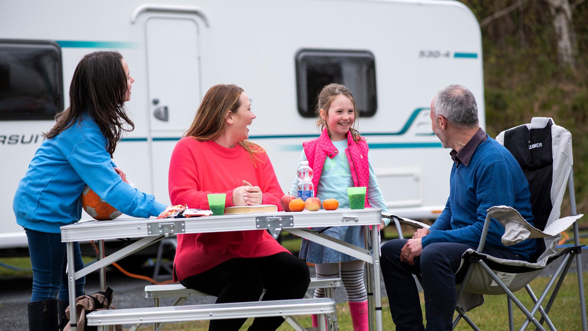 Family at table outside caravan