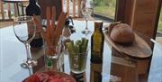 Glass topped dining table laid with Wine bottle  and 2 wine glasses, salad,  breads and salad dressing  View out through glass patio doors onto patio
