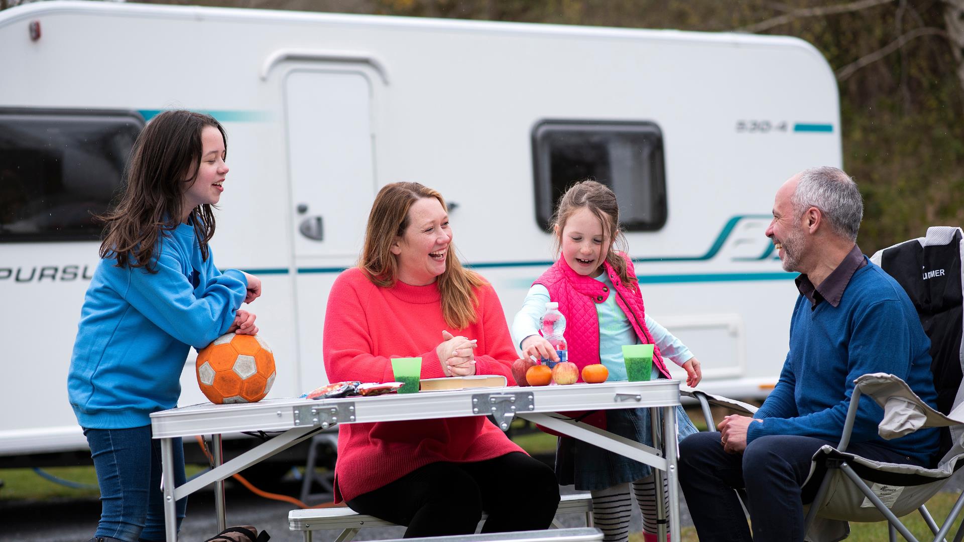 Family of four enjoying at snack outside their caravan