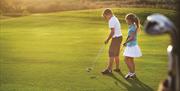 A young boy and girl playing golf on a golf course.