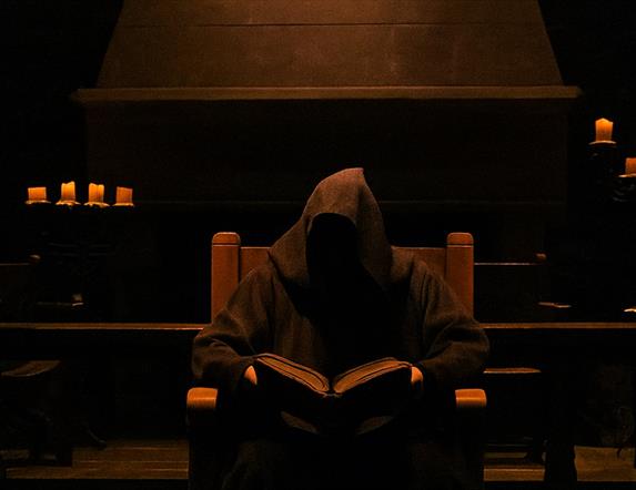 Hooded figure storyteller sitting in Winterfell Hall