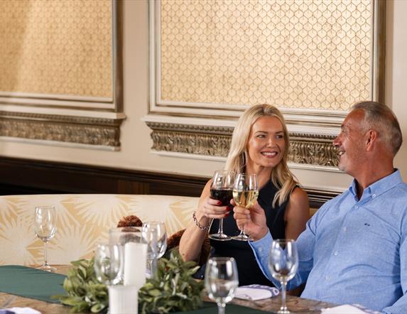 Female and male holding wine glasses at a table in The Gallery of The Old inn