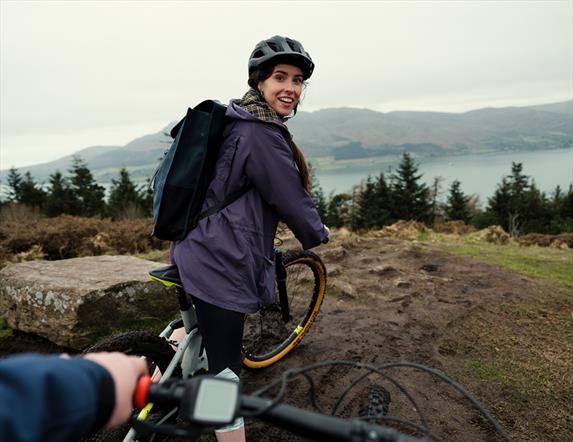 Image shows couple biking and the lady is looking back at her partner