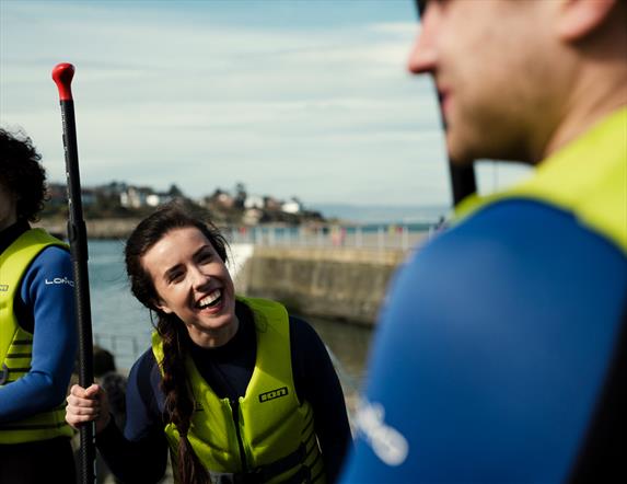 Image shows a group of people enjoying stand-up paddle boarding