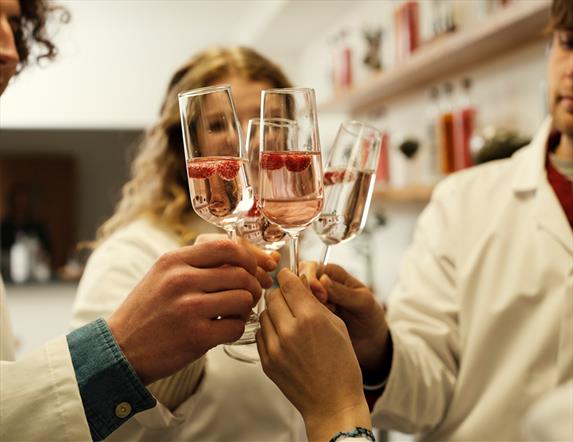 Image shows four champagne glasses in a circle being held by four people