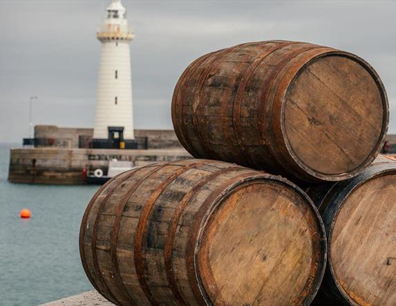 Three barrels stacked in a triangle on Donaghadee Pier with the lighthouse in the background