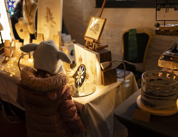 Little girl looking at glasswork crafts at Castle Ward