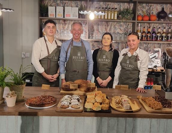 Staff from Bistro at the Courthouse stand behind the restaurants counter, with plenty of bakes and sweet treats in front of them