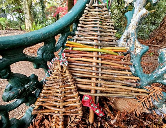 WILLOW CHRISTMAS TREES SITTING ON A GARDEN BENCH