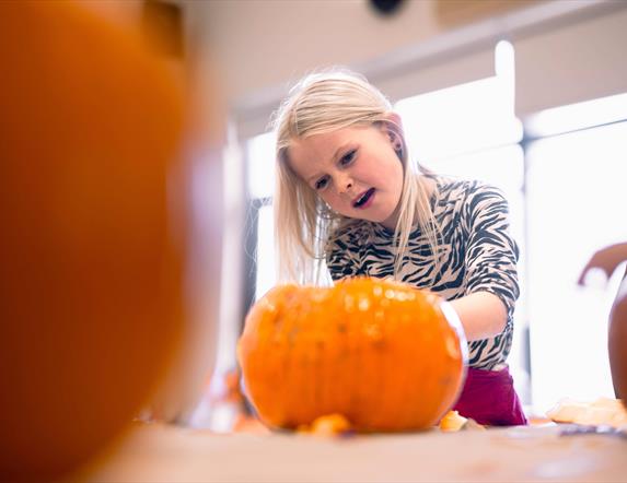 child carving pumpkin