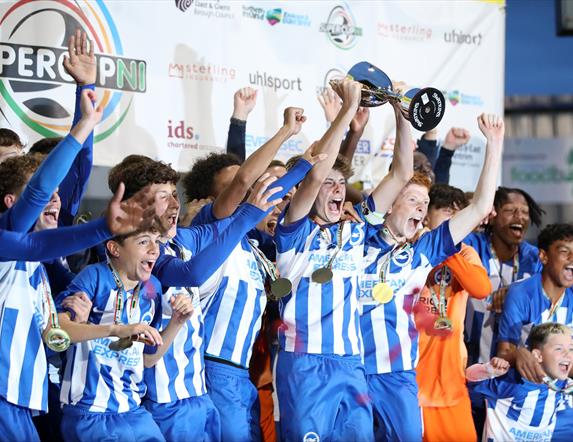 a male youth football team celebrates winning a trophy