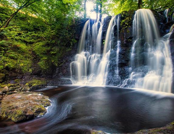 Water flowing over the rocks in Glenariff Forest with green trees surrounding the pool of water