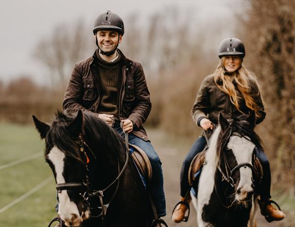 a man and woman on horseback on a countryside trail