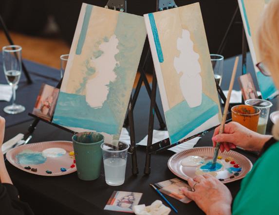 Image of a paint & prosecco session at the Ulster Museum showing two women painting canvases.