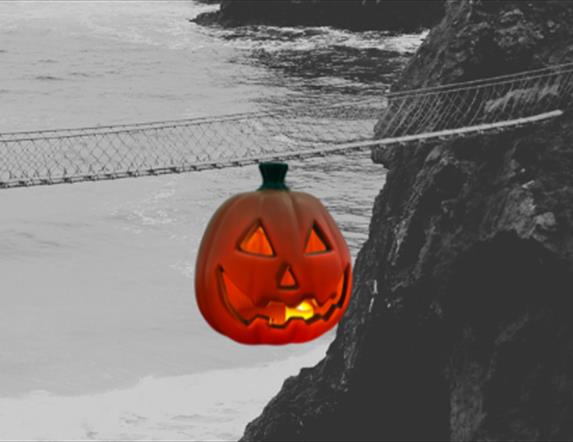 Black and White Picture of Carrick-a-Rede Rope Bridge  for Halloween, with a pumpkin graphic hanging from the bridge