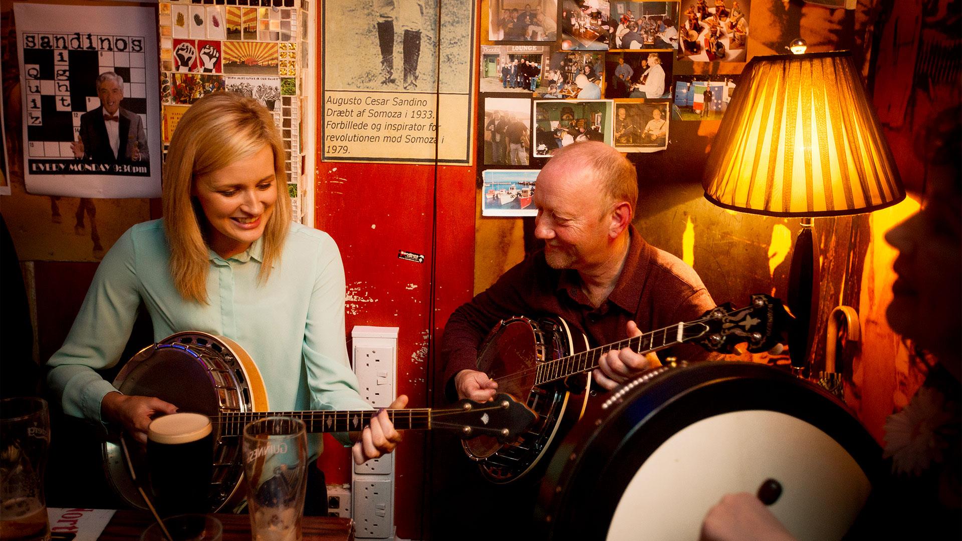 Couple playing the banjo infront of a table of drinks at the Café Bar, Derry-Londonderry.