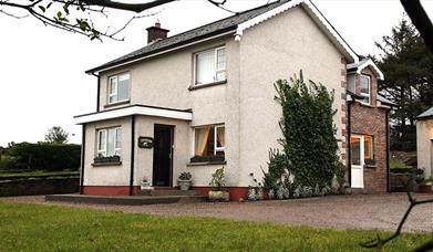 Image of a white two story house with climbing vines up the side