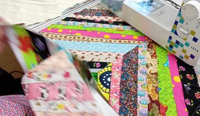 Sewing machine and patchwork quilt in progress at Midtown Makers workshop