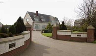 Walled driveway leading to a large lodge.